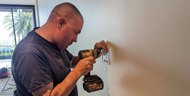 electrician doing wiring on the wall of a home