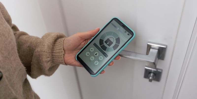 Person holding a smart phone that operates a smart door lock. 